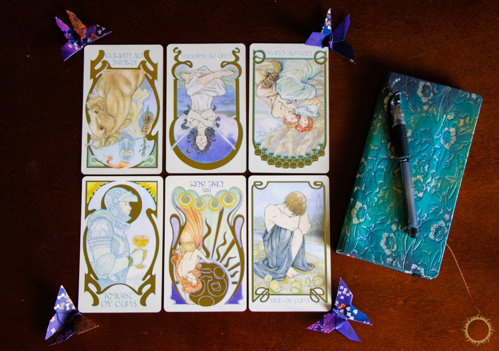 Tarot cards, a journal, pen, and origami butterflies